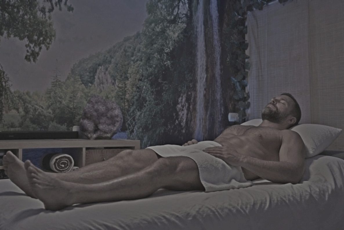 A man lying on his back with his hands resting on his chest and belly during a breathing session