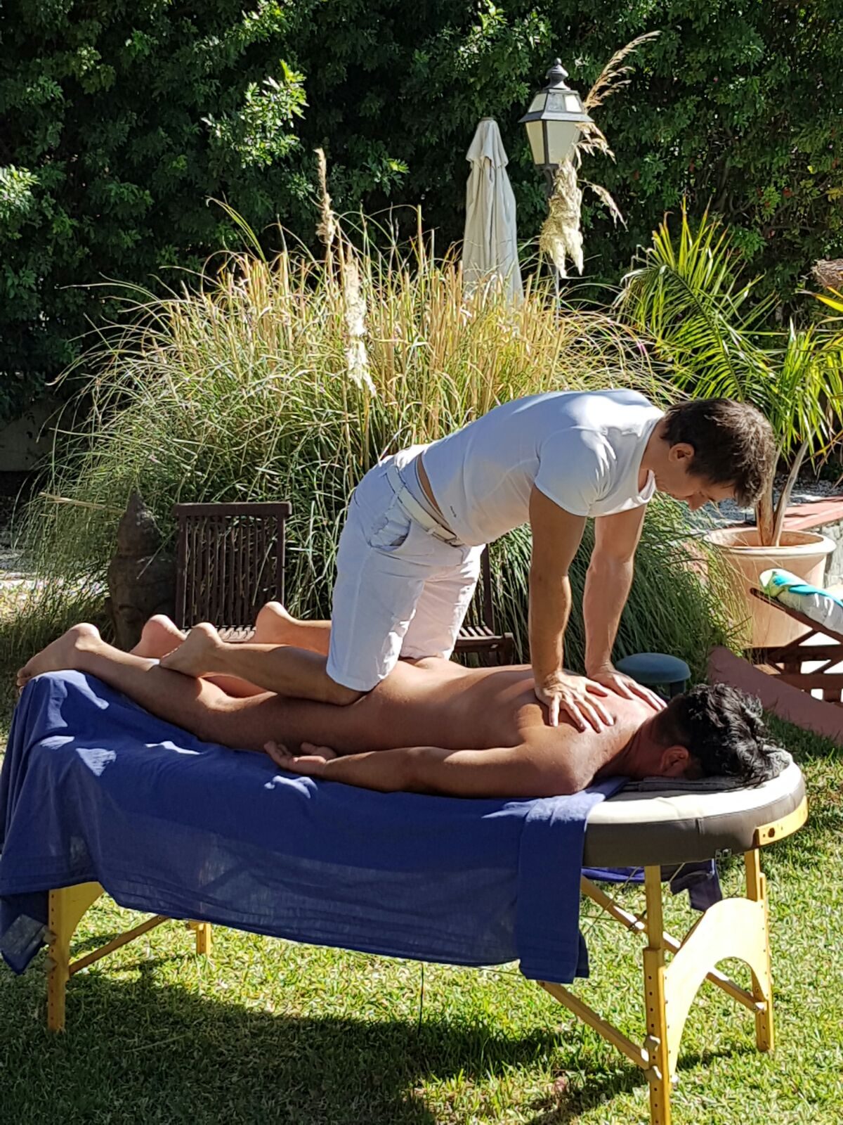 Massage table set up outdoors in a garden in Maspalomas, Gran Canaria, a man receiving a full body massage